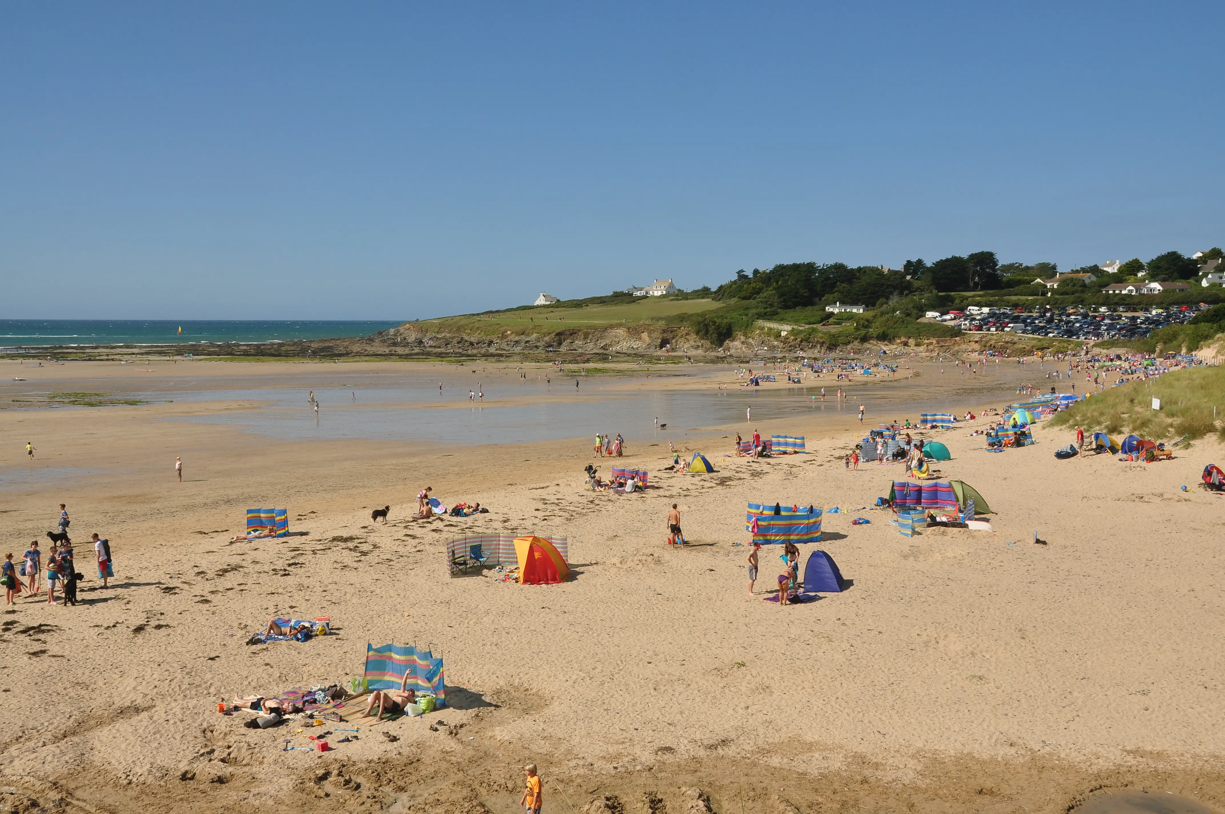 Daymer Bay at low tide — fine sand and gentle estuary water with dunes behind.