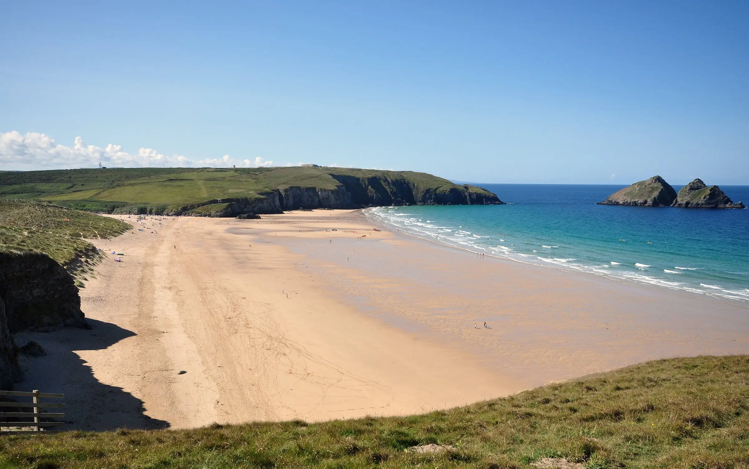 Holywell Bay — dune-backed beach with the Gull Rocks visible offshore.