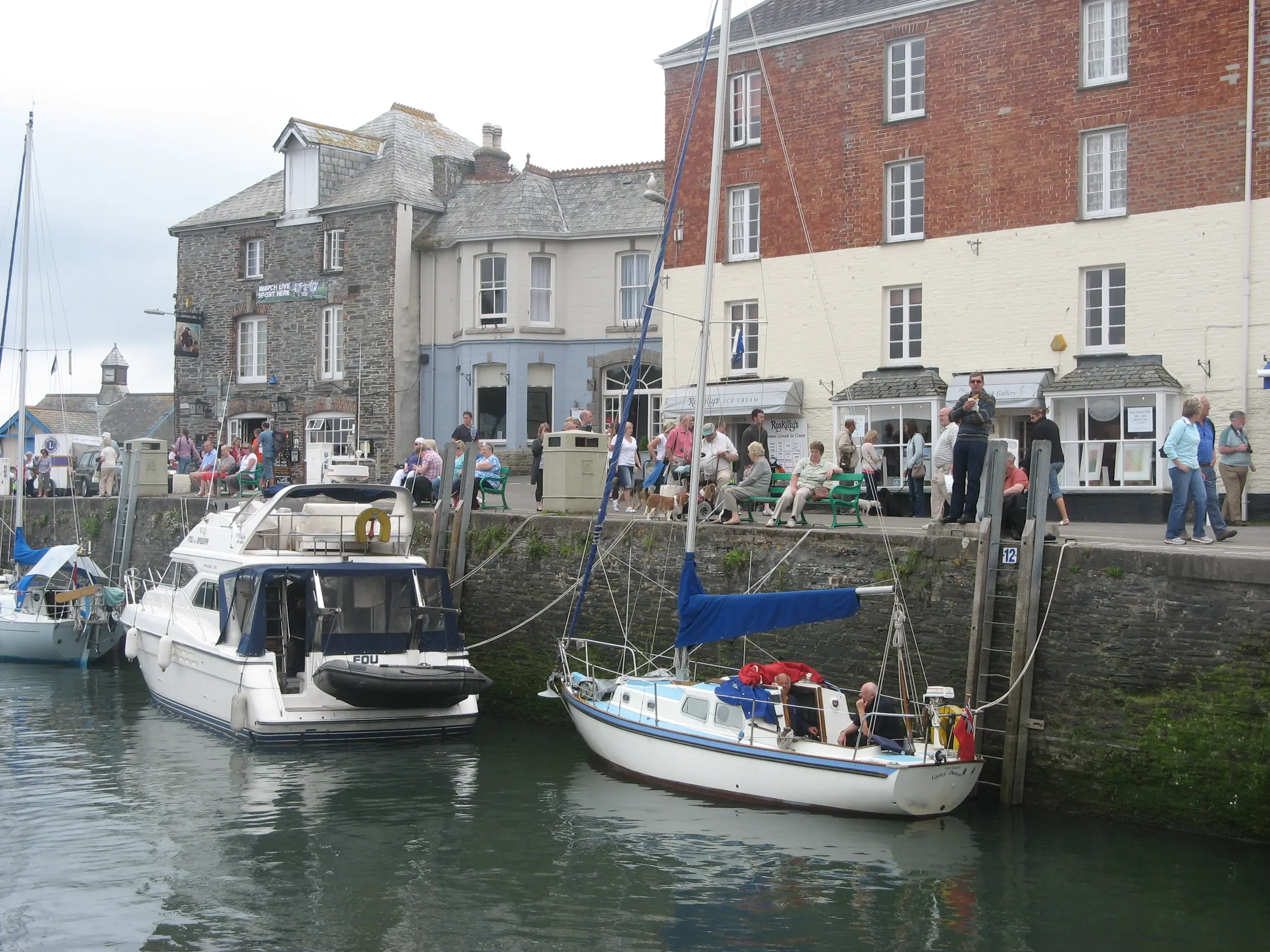 Padstow harbour — fishing boats moored in the estuary, with the town's restaurants and shops behind.