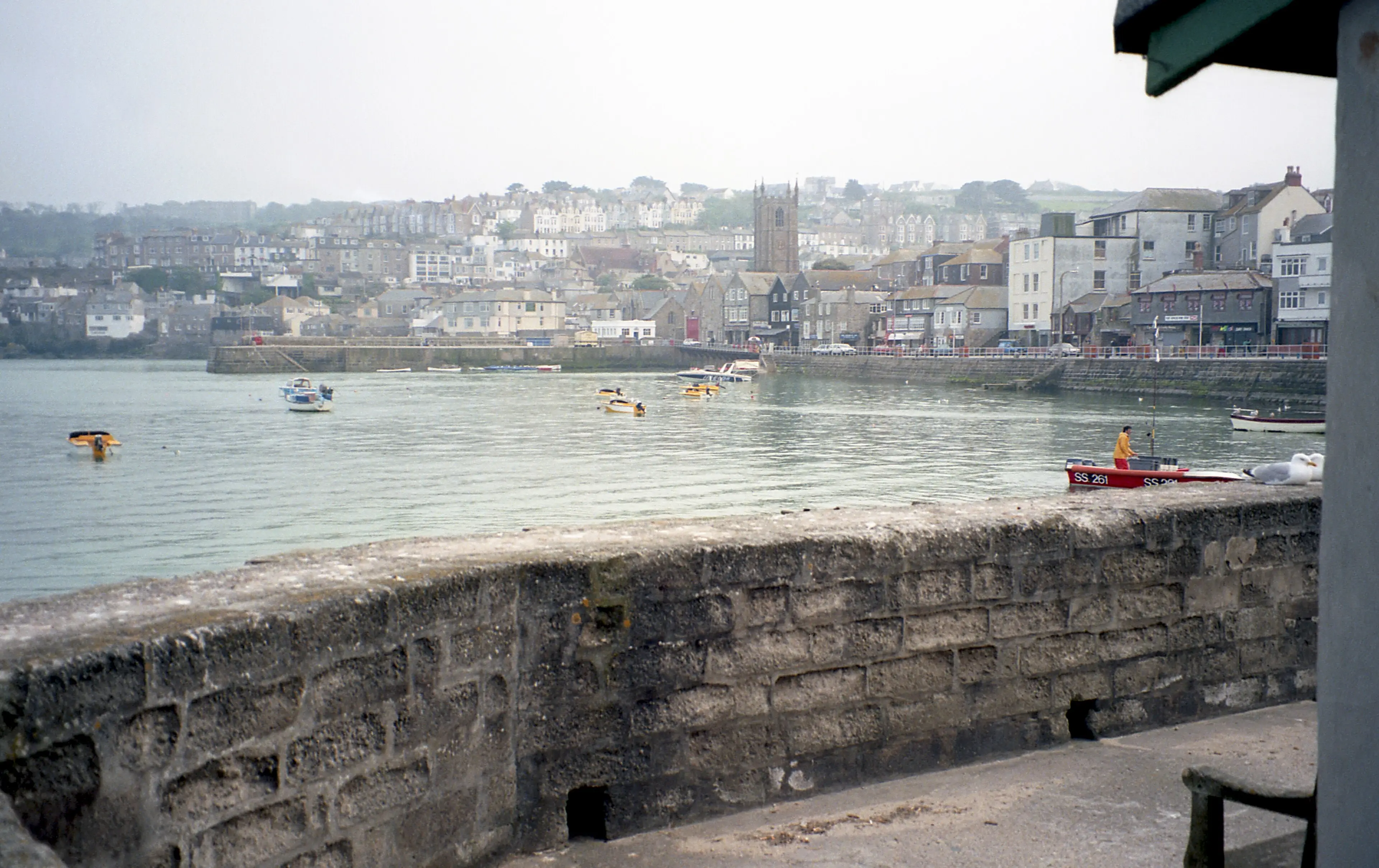 St Ives harbour at golden hour — the curving harbour wall, pastel-painted cottages, and the light that attracted generations of artists.
