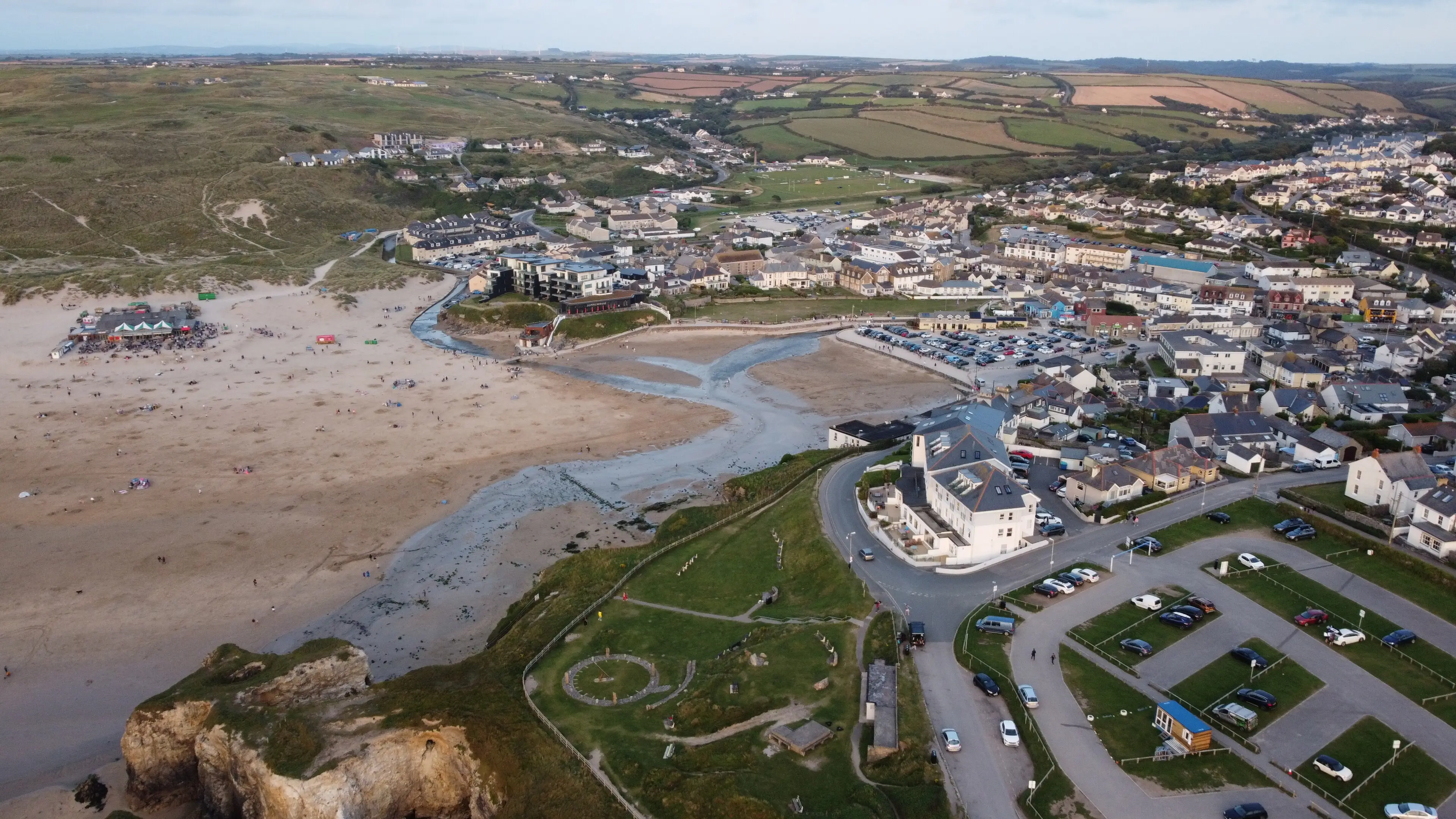 Perranporth beach — three miles of golden sand stretching towards the dunes, with surfers dotting the waterline.