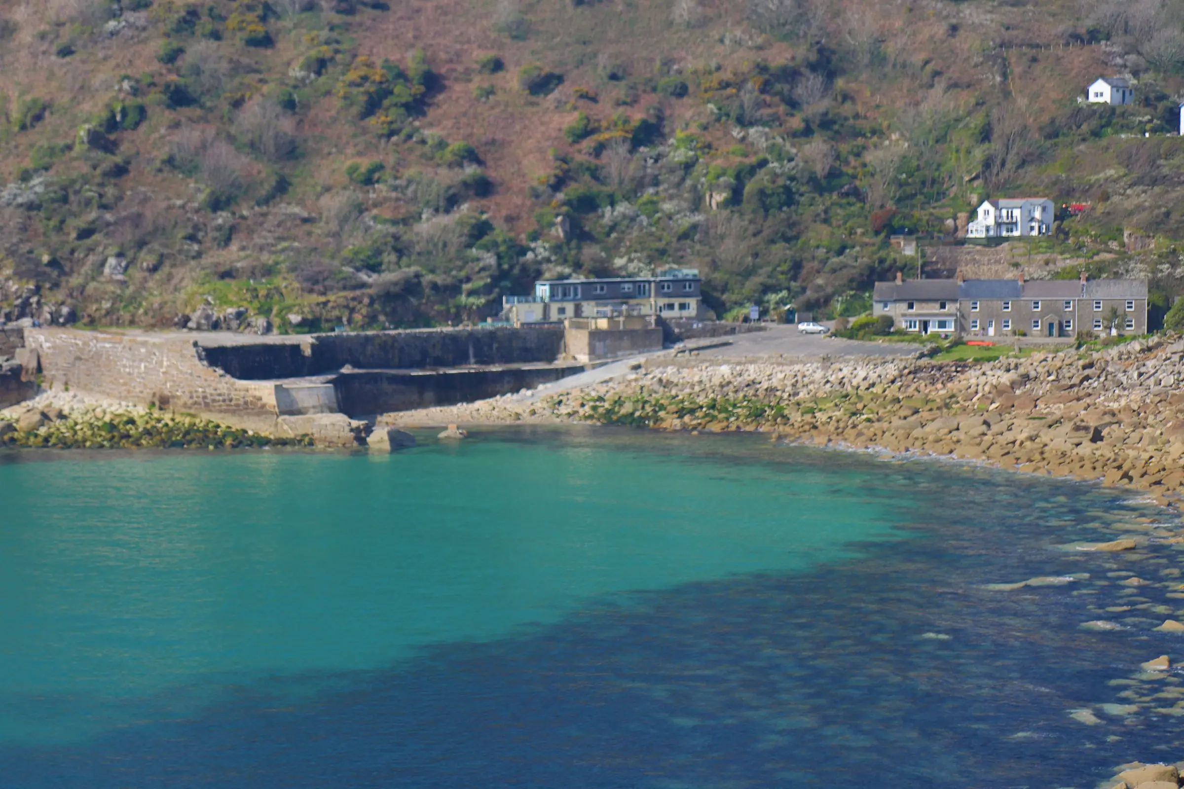 Lamorna Cove — granite cliffs framing turquoise water and a rocky beach on Cornwall’s south coast.